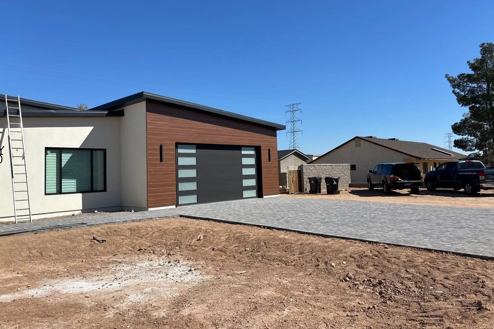 Black modern garage door with frosted side windows on a flat-roof stucco and wood home