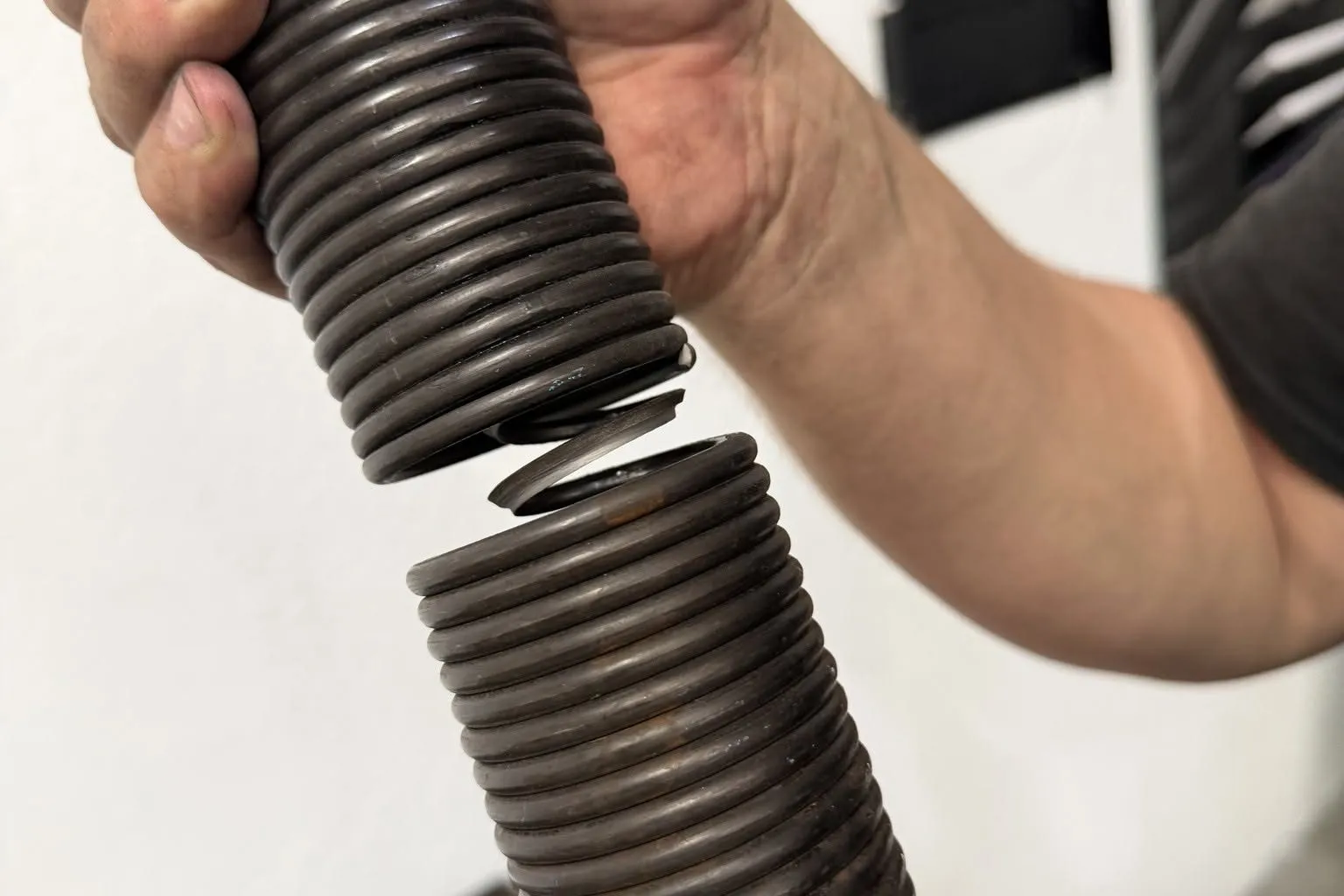 Hand holding a garage door torsion spring that has broken into two pieces
