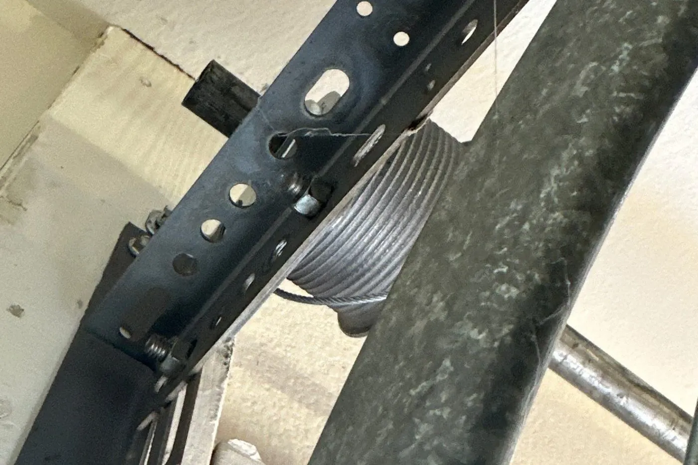 Lift cable wound on its drum beside the curved track and a perforated angle bracket