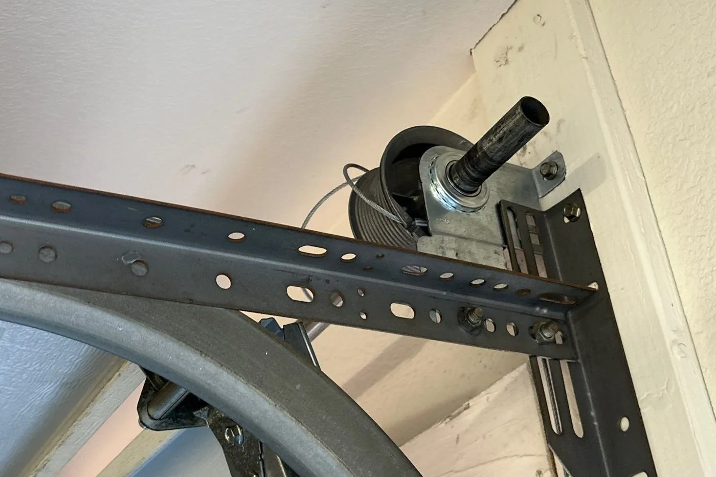 Garage door cable drum, shaft and track bracket mounted above the door