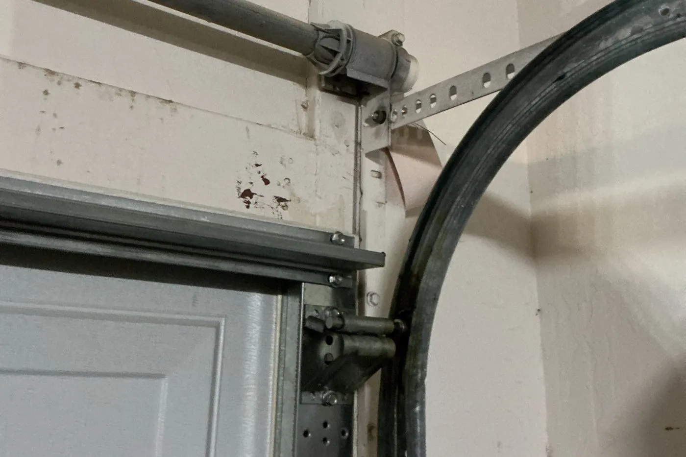 Curved garage door track and roller at the top corner of a door