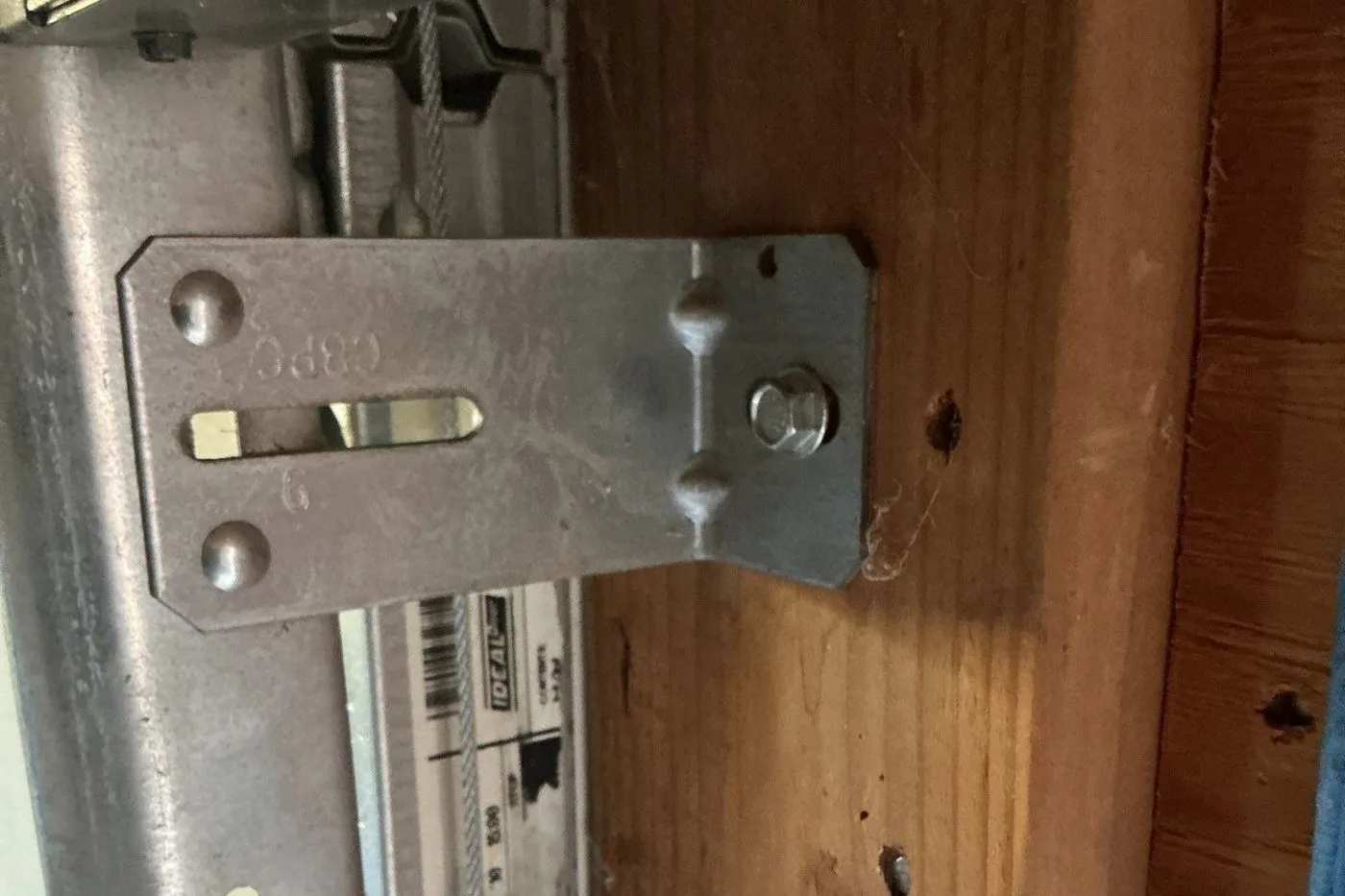 Galvanized flag bracket and vertical track bolted to the wood door jamb