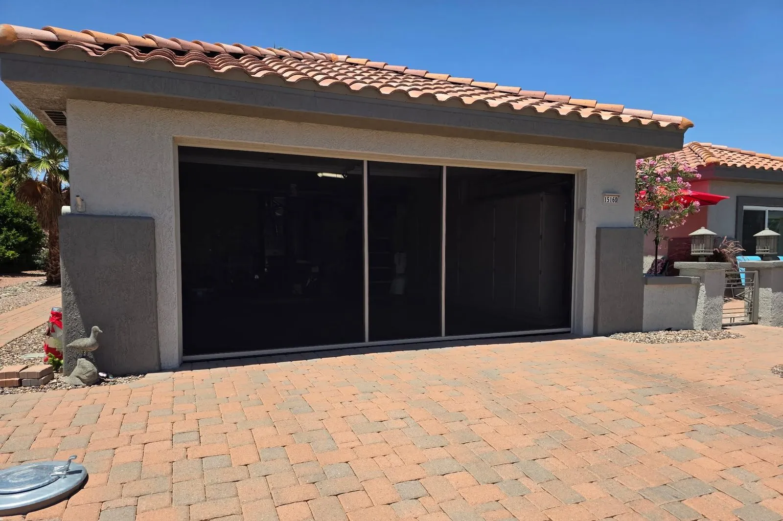 Retractable screen across a two-car garage opening above a paver driveway