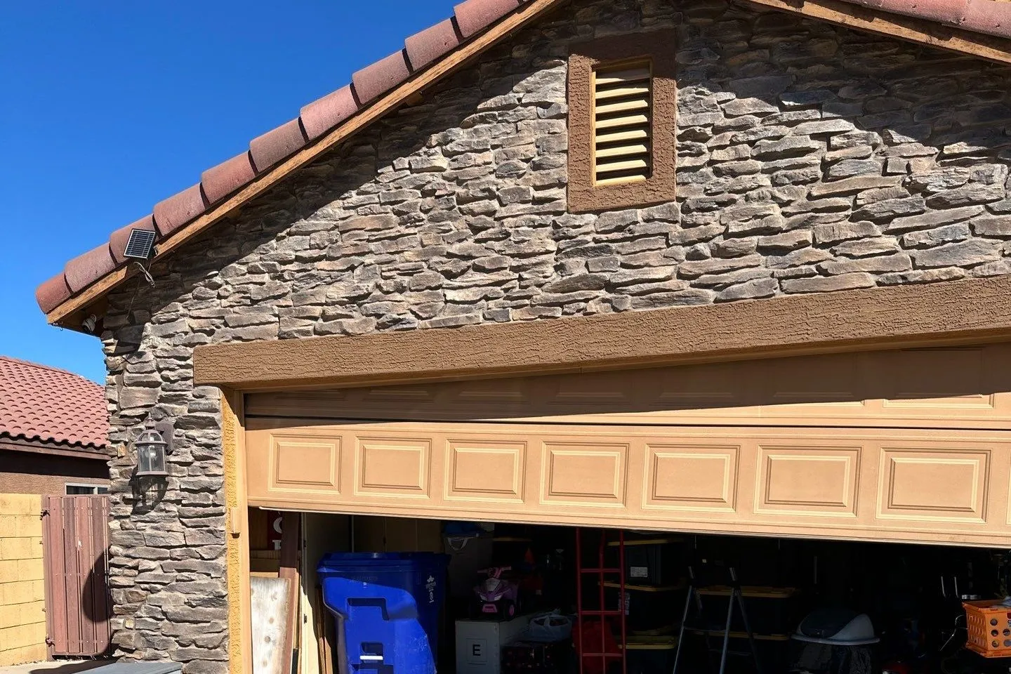 Garage door stopped partway open on a stone-faced gable home