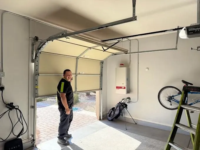 Technician standing in a garage beside a partly raised garage door