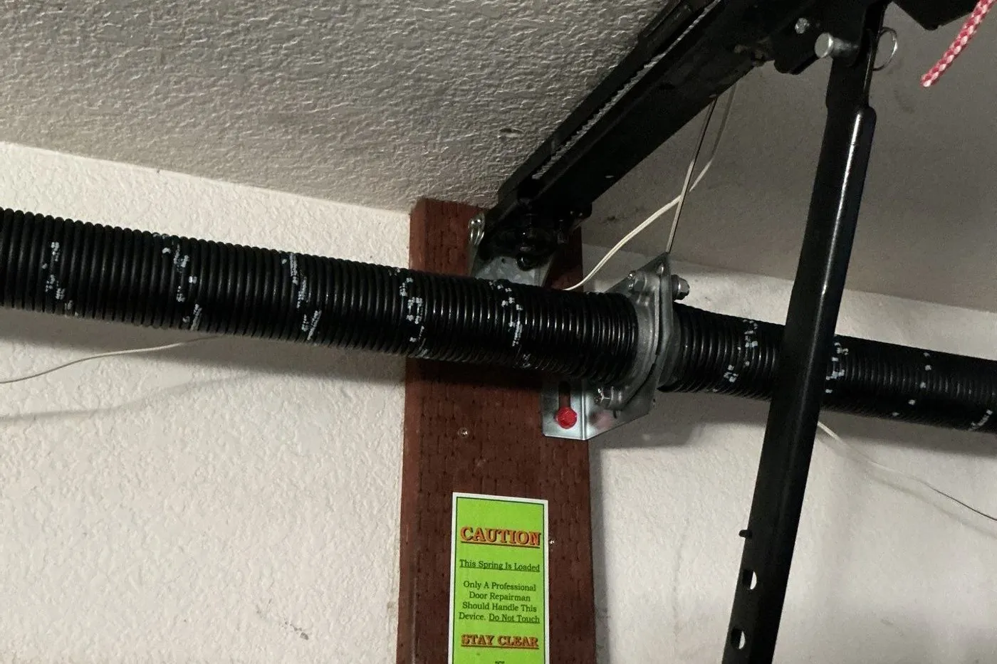 Black torsion spring and center bearing bracket with a caution label on the header board