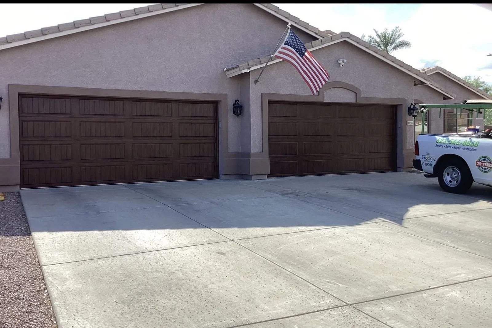 Two dark wood-tone garage doors on a stucco home with a tile roof