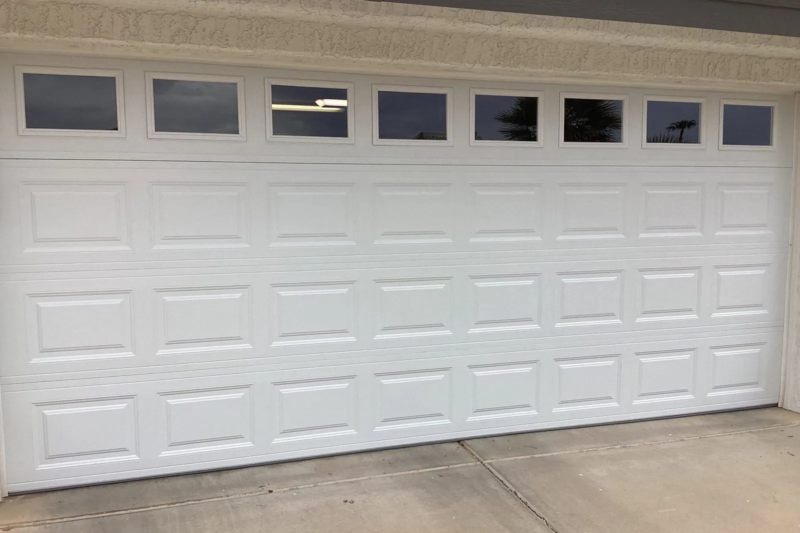 White raised-panel garage door with a row of windows across the top