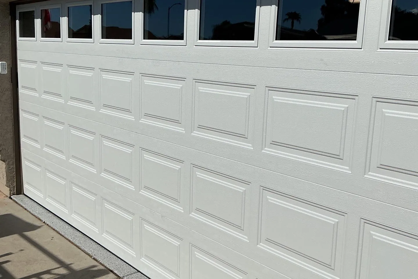 White raised-panel garage door with a row of windows across the top
