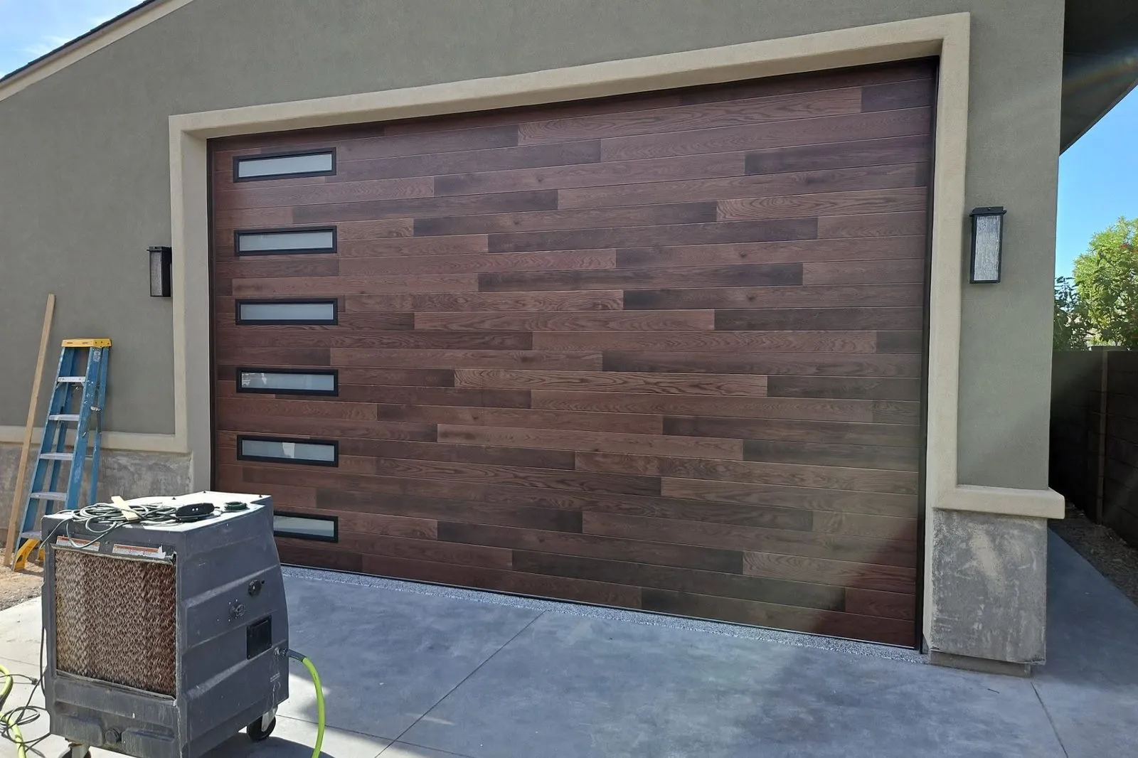Wood-look garage door with narrow horizontal windows on a stucco home